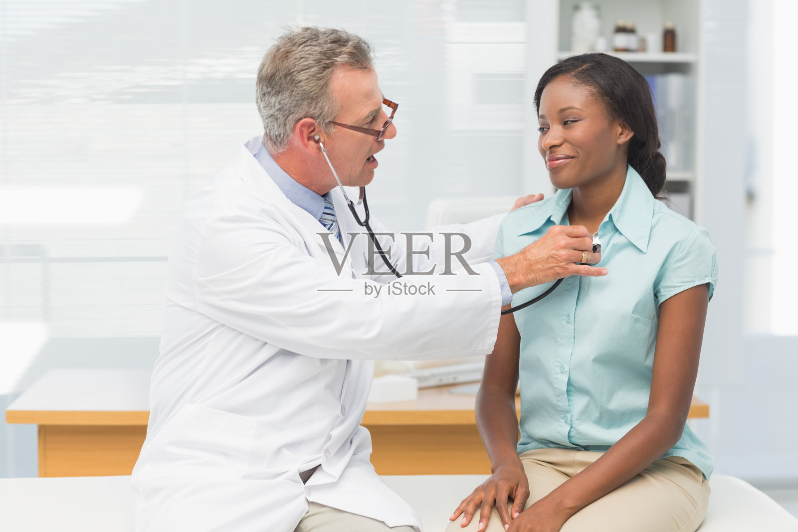 医生用听诊器听诊心情愉快的病人的胸部照片摄影图片