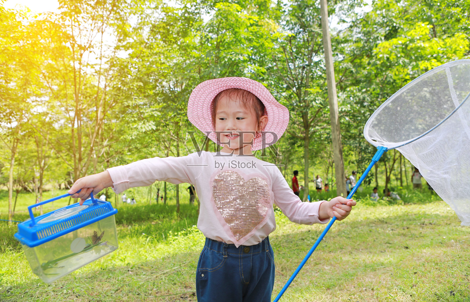 亚洲女孩戴着草帽，戴着蚊帐在地里玩耍。照片摄影图片