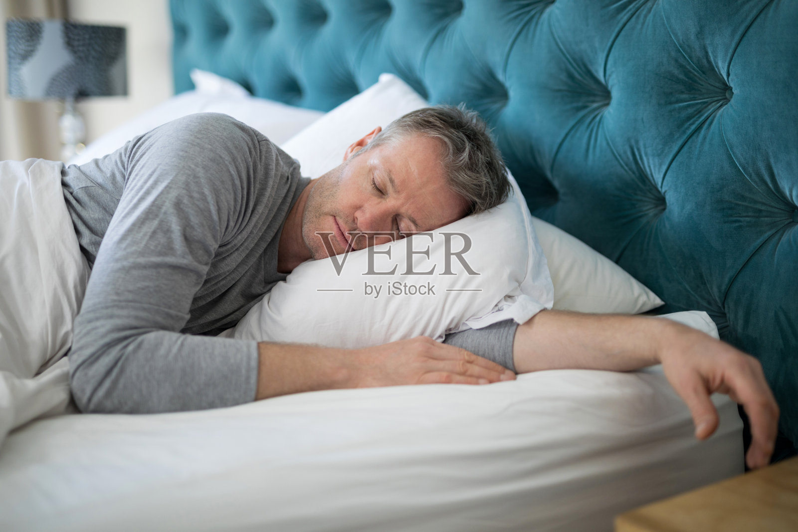 一个男人睡在卧室的床上照片摄影图片