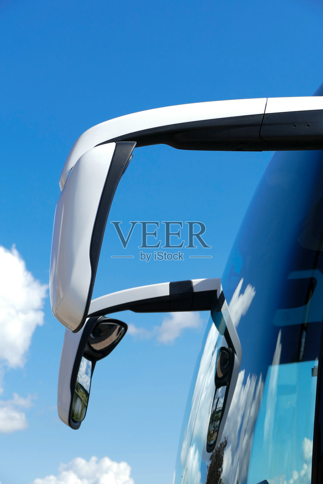 在一辆现代旅游巴士上，前面有两个巨大的侧视镜，背景是蓝天照片摄影图片