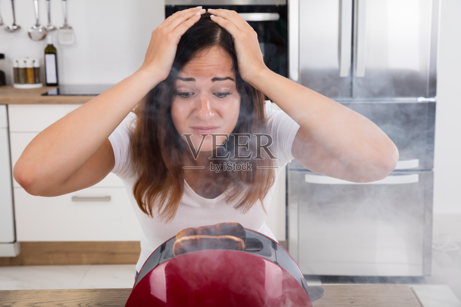沮丧的女人看着烤面包机里烧焦的土司照片摄影图片