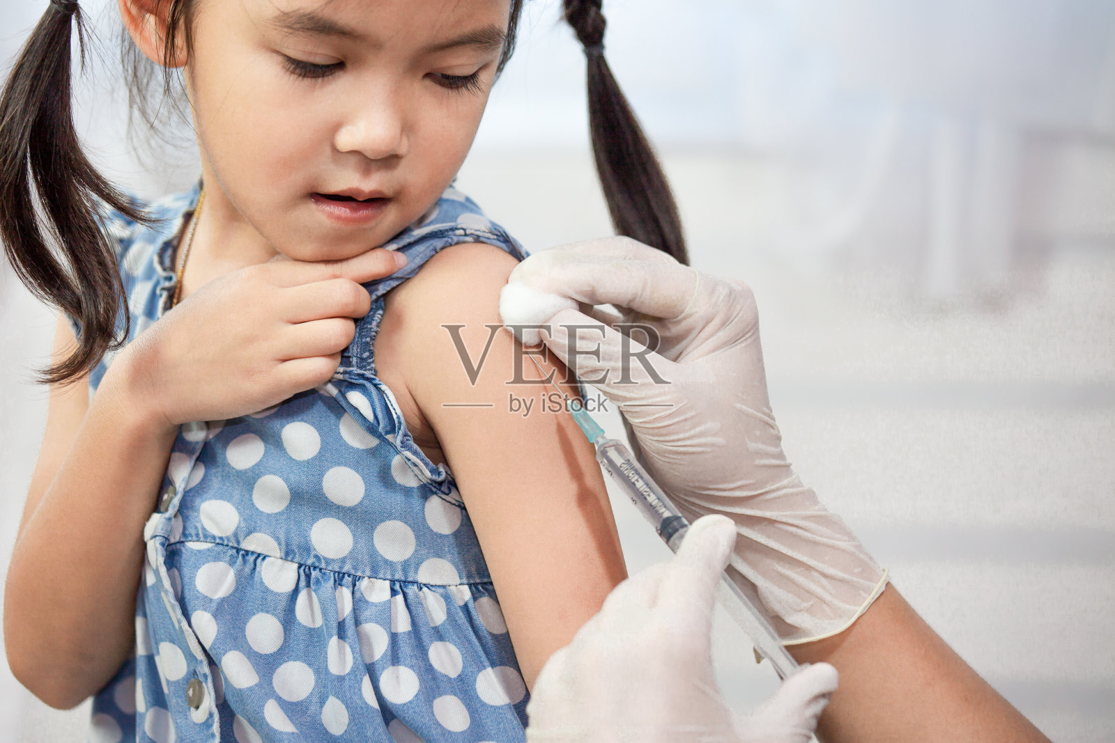 医生在亚洲小女孩的手臂注射疫苗照片摄影图片