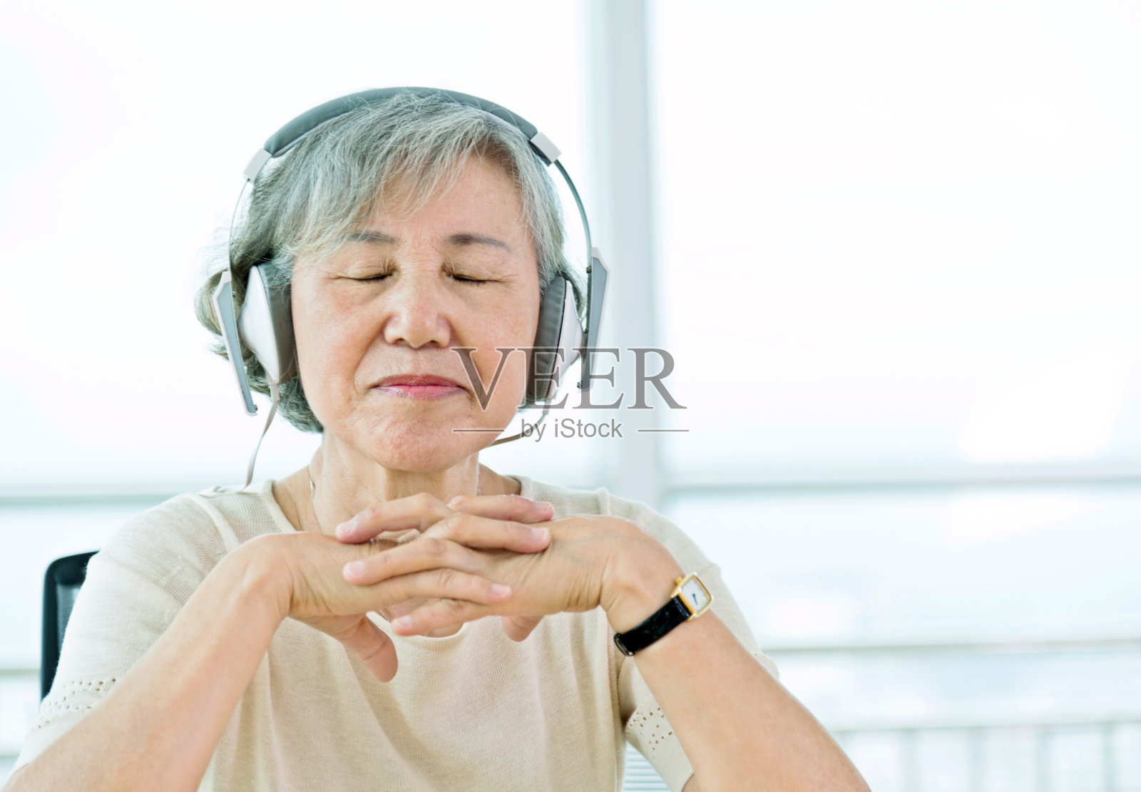 一位年长的亚洲女性正戴着耳机听音乐照片摄影图片