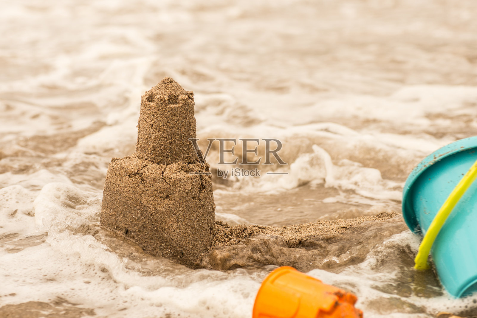 执着的沙堡塔被海水冲走了。照片摄影图片