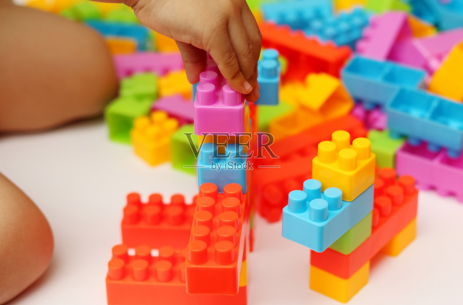 儿童的手构建塑料玩具积木与模糊的背景照片摄影图片