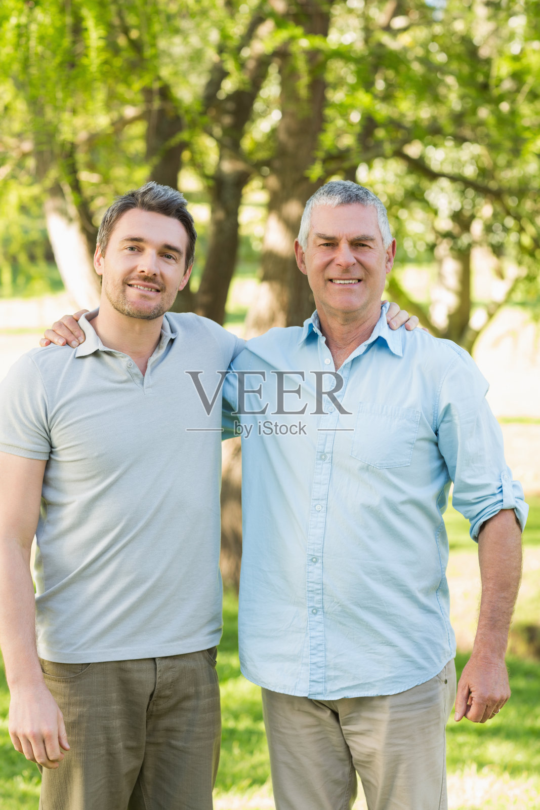 微笑的父亲和成年的儿子在公园照片摄影图片
