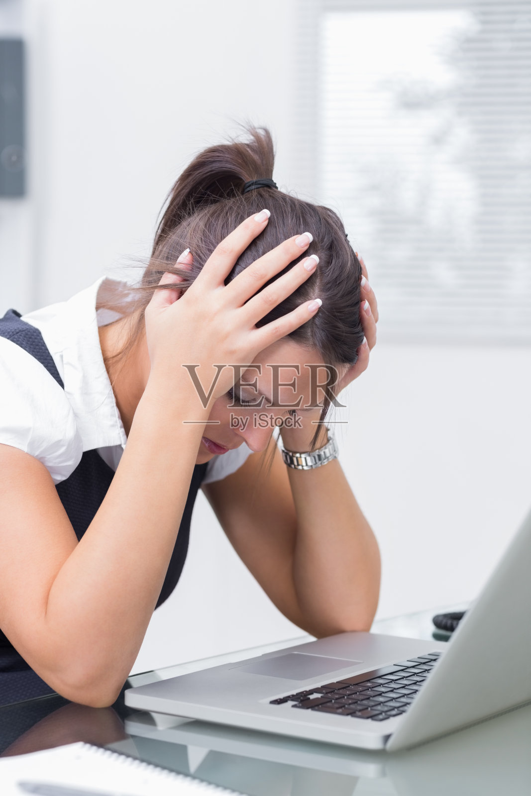 沮丧的女商人双手抱头坐在笔记本电脑前照片摄影图片