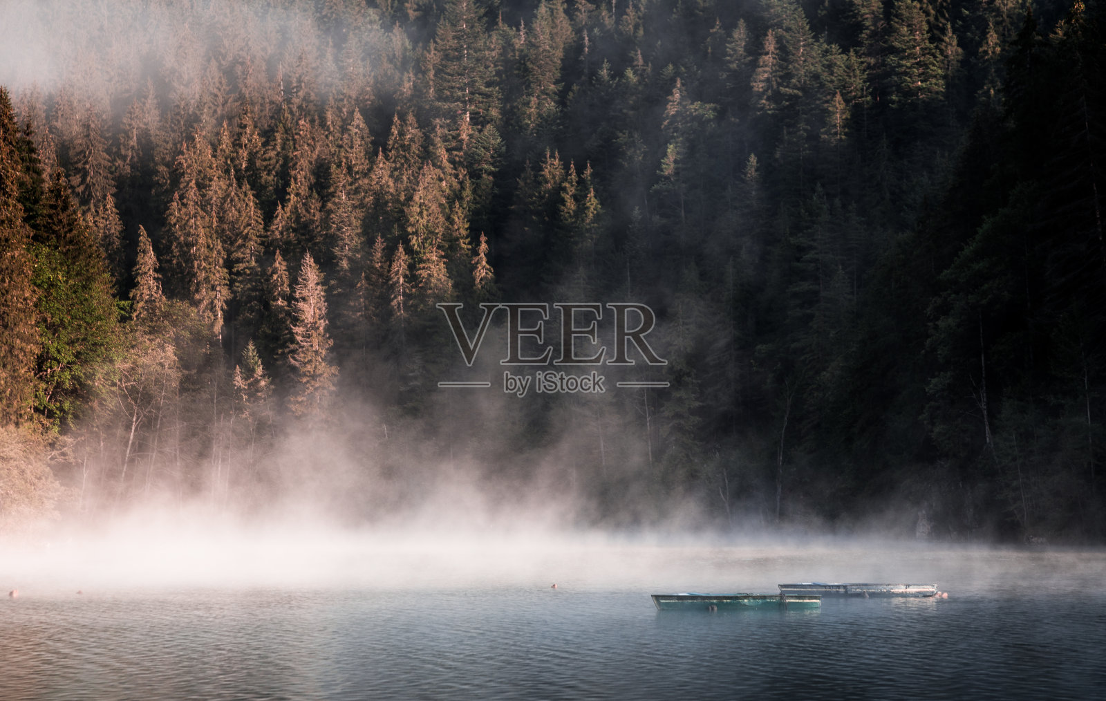 清晨的湖面上有薄雾，有森林，有小船照片摄影图片