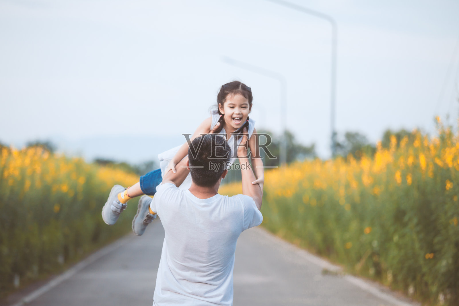 快乐的亚洲父亲抱着他的孩子旋转在公园的乐趣照片摄影图片