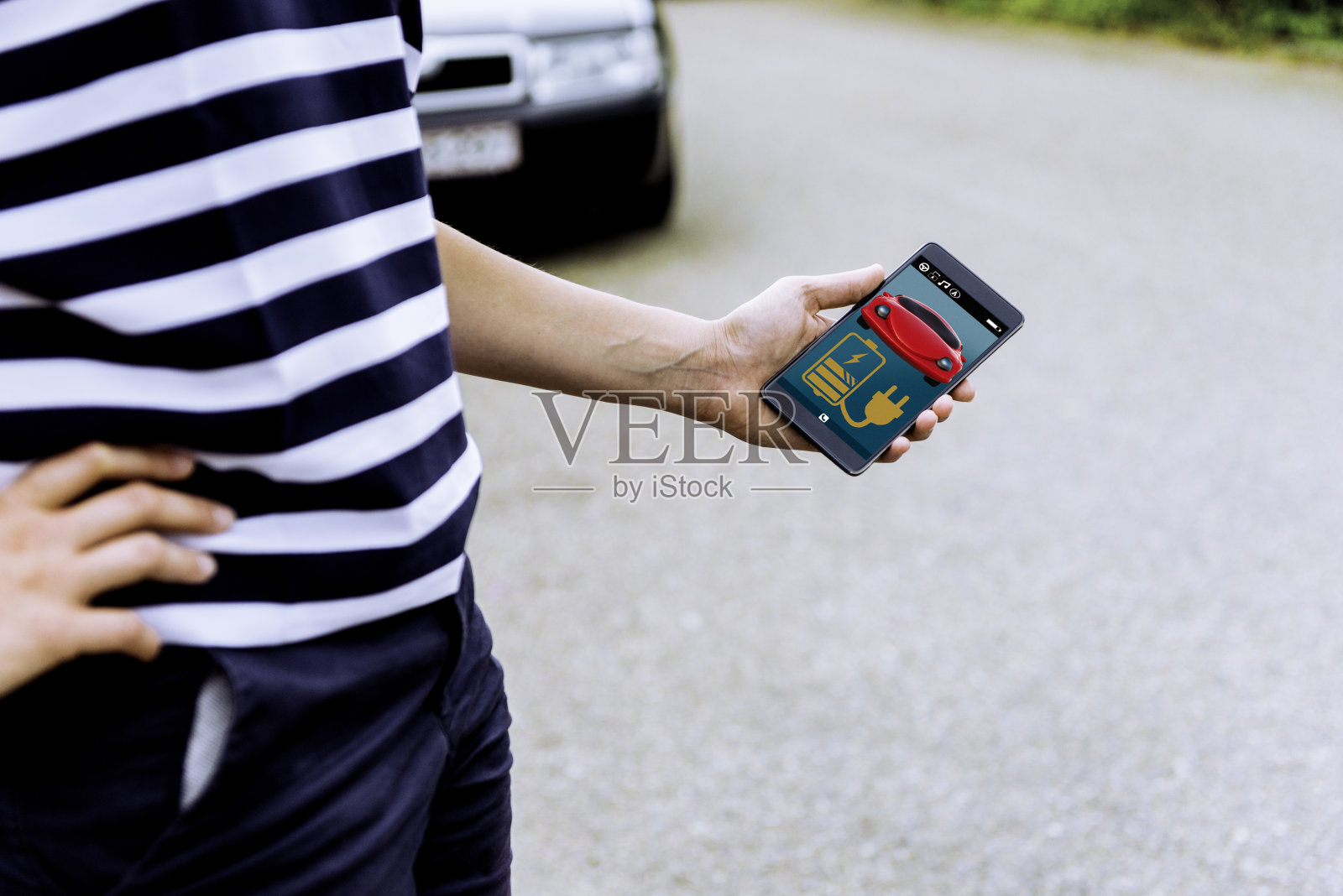 女人看应用程序，以获得关于她的电动汽车电池消耗的信息照片摄影图片