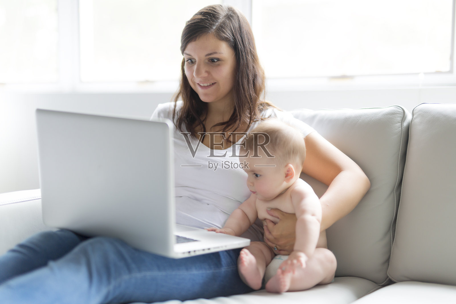 母亲和婴儿都希望在家里的沙发上玩和阅读电脑照片摄影图片