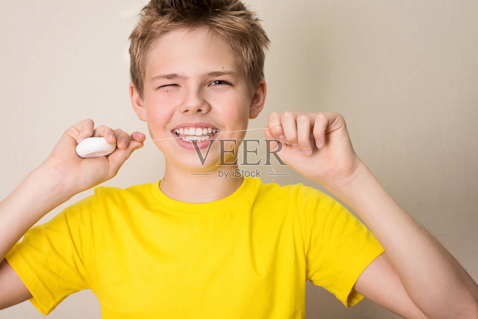 男孩用牙线清洁牙齿。特写的十几岁的男孩与牙线孤立。照片摄影图片