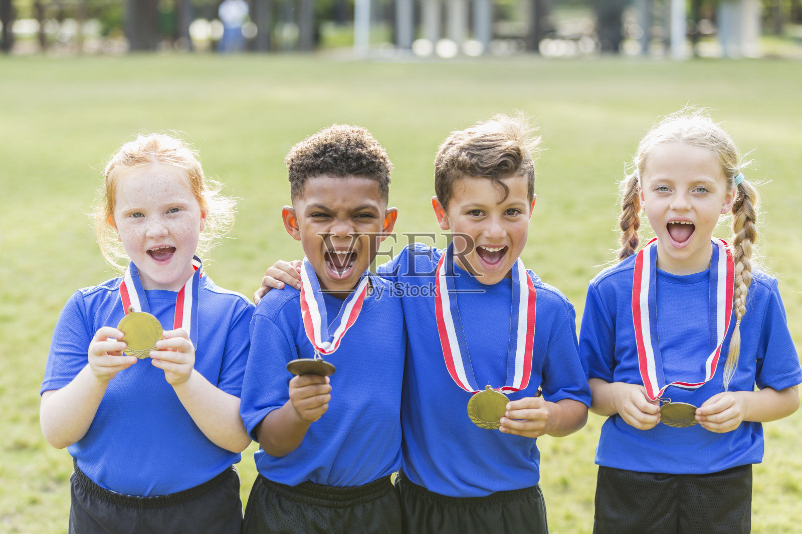 多民族儿童获胜的团队，与奖牌照片摄影图片