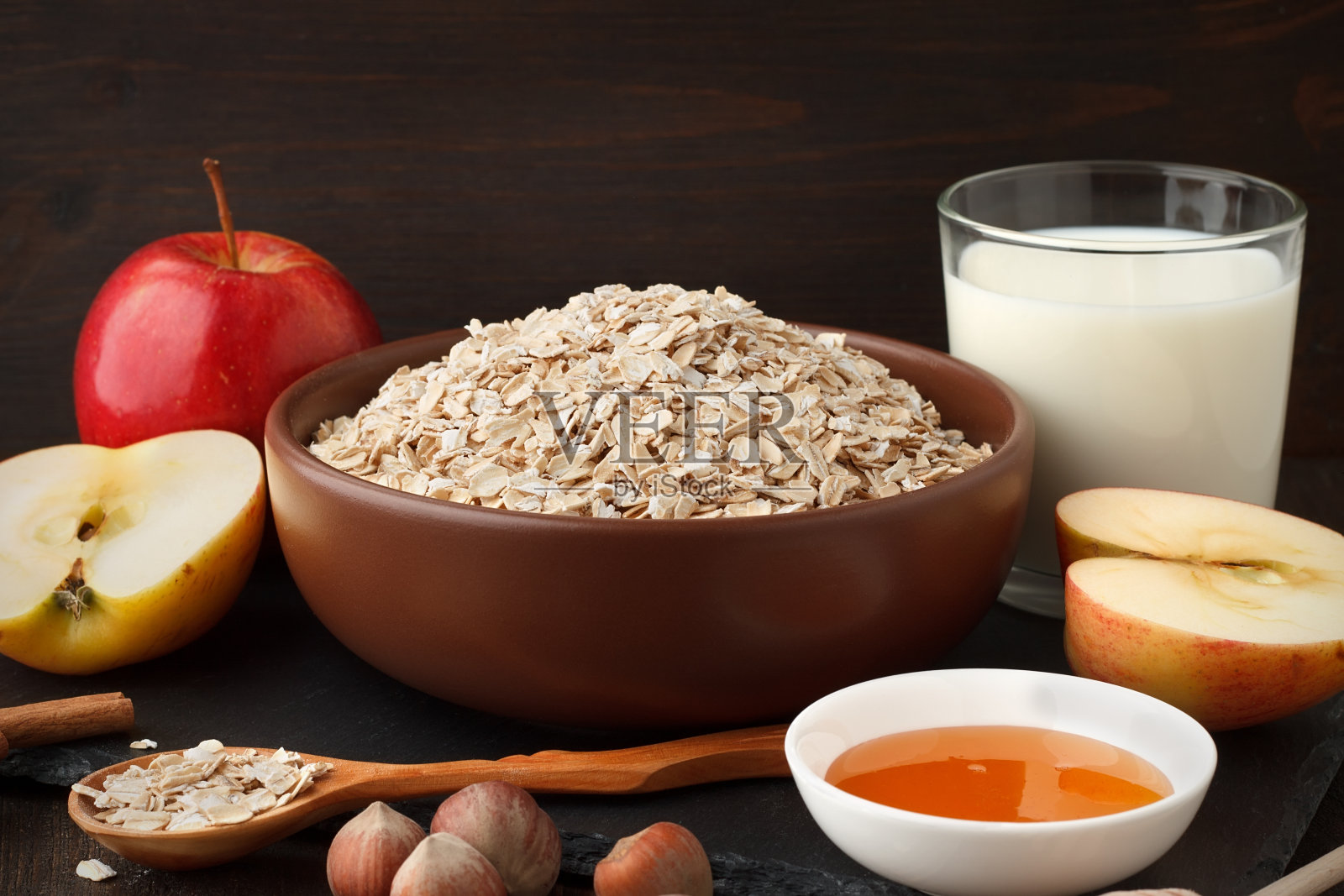 健康早餐的原料。碗里有燕麦片，苹果，牛奶，蜂蜜。照片摄影图片