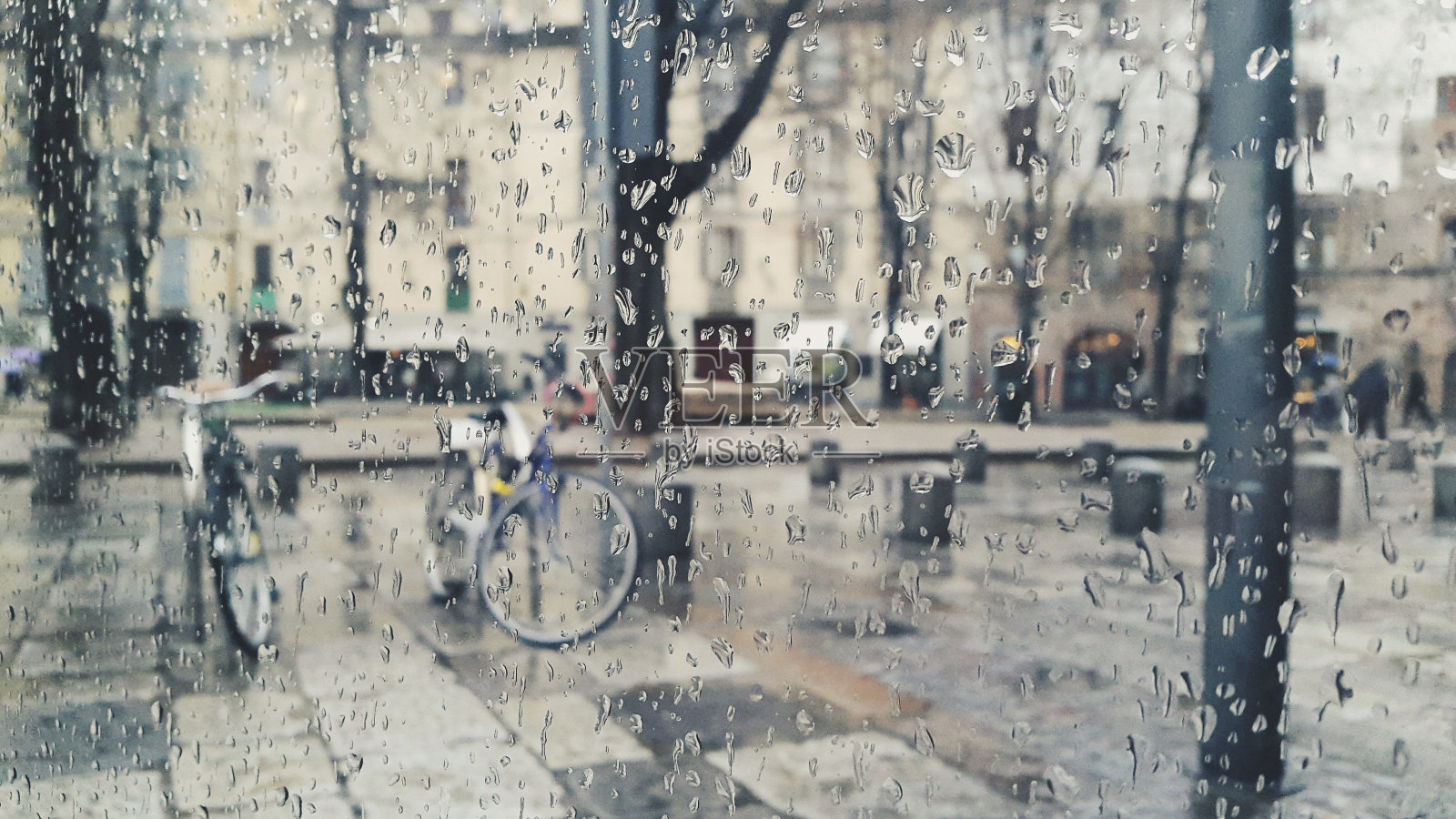 雨点落在雾气蒙蒙的庭院玻璃门上，俯瞰郊外的街道照片摄影图片