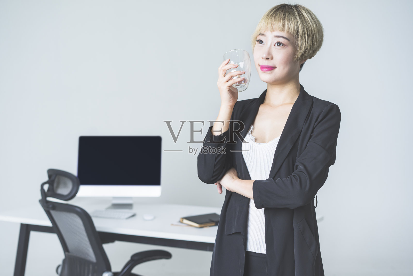 职场女性在办公室边喝水边思考照片摄影图片