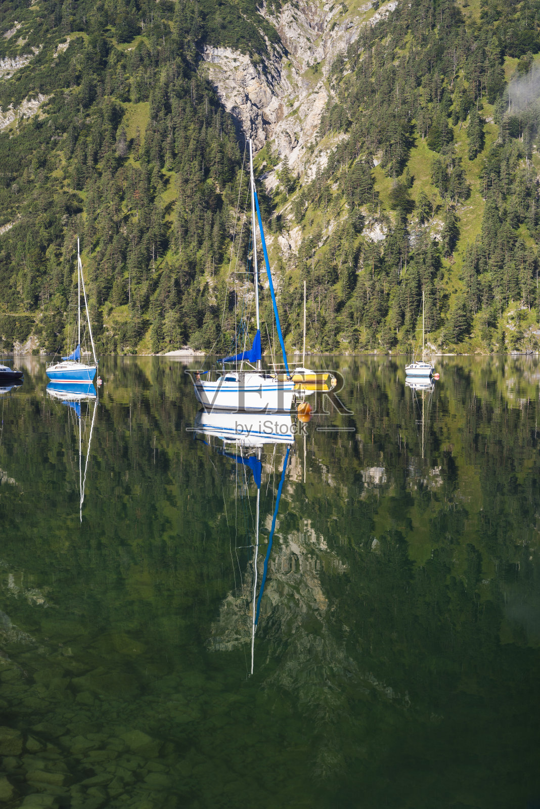 秋天，奥地利蒂罗尔，帆船和游艇停泊在阿钦湖平静的湖面上，与山坡相映成趣照片摄影图片