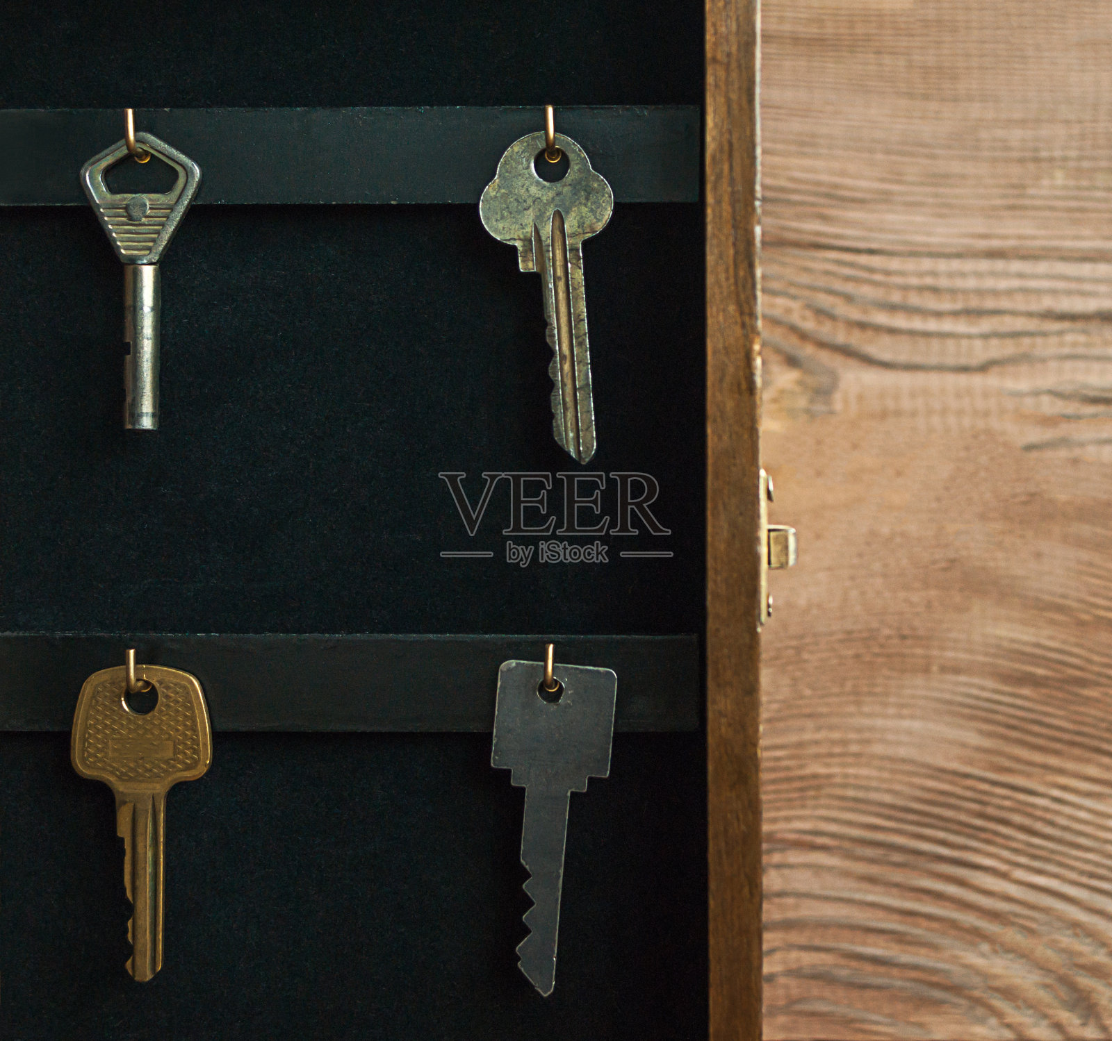 组织您的生活，保险和安全概念:古董打开木质钥匙架盒柜，钥匙挂在金色挂钩，质朴的木制背景。照片摄影图片