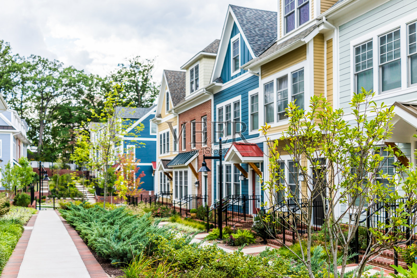 一排排五颜六色的、红的、黄的、蓝的、白的、绿的住宅联排别墅，在夏天有砖砌的庭院花园照片摄影图片