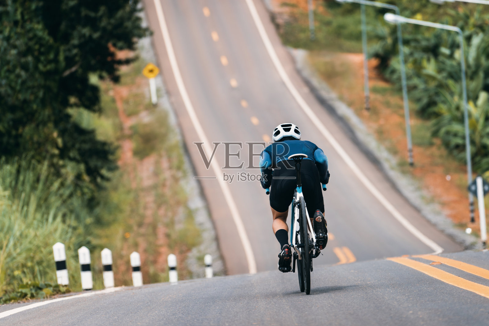骑车者调整姿势以减少空气阻力。骑着自行车下山。照片摄影图片