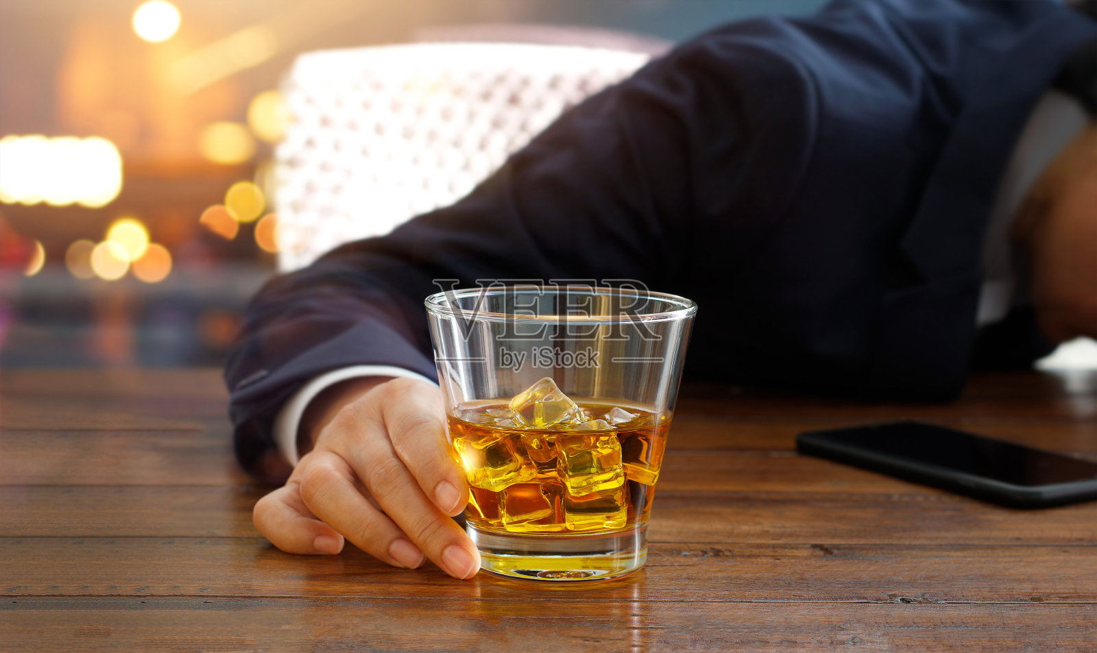 商人手里拿着波旁威士忌，醉醺醺地睡在酒吧的桌子上照片摄影图片