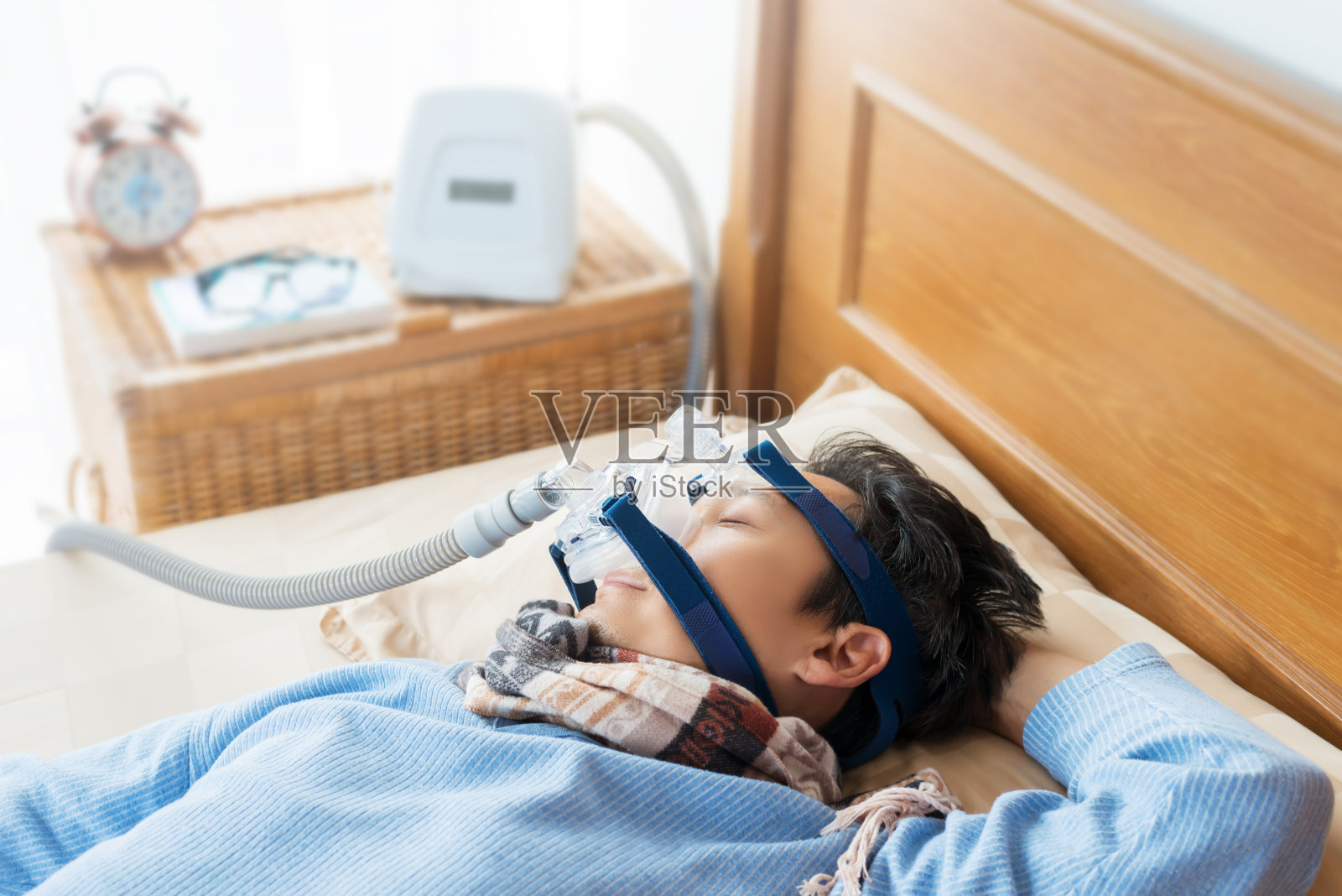 男人躺在床上戴着CPAP口罩，这是医疗理念。照片摄影图片
