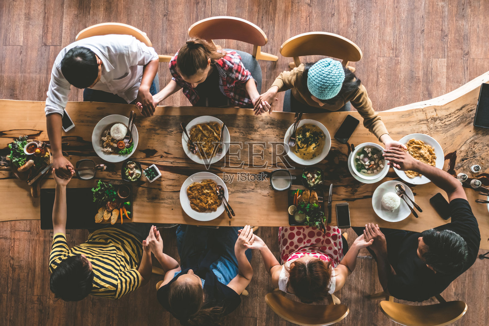 一群朋友聚在一起祈祷，享用美味的食物和饮料，享受聚会和交流，俯瞰家人聚在一起吃晚餐。照片摄影图片