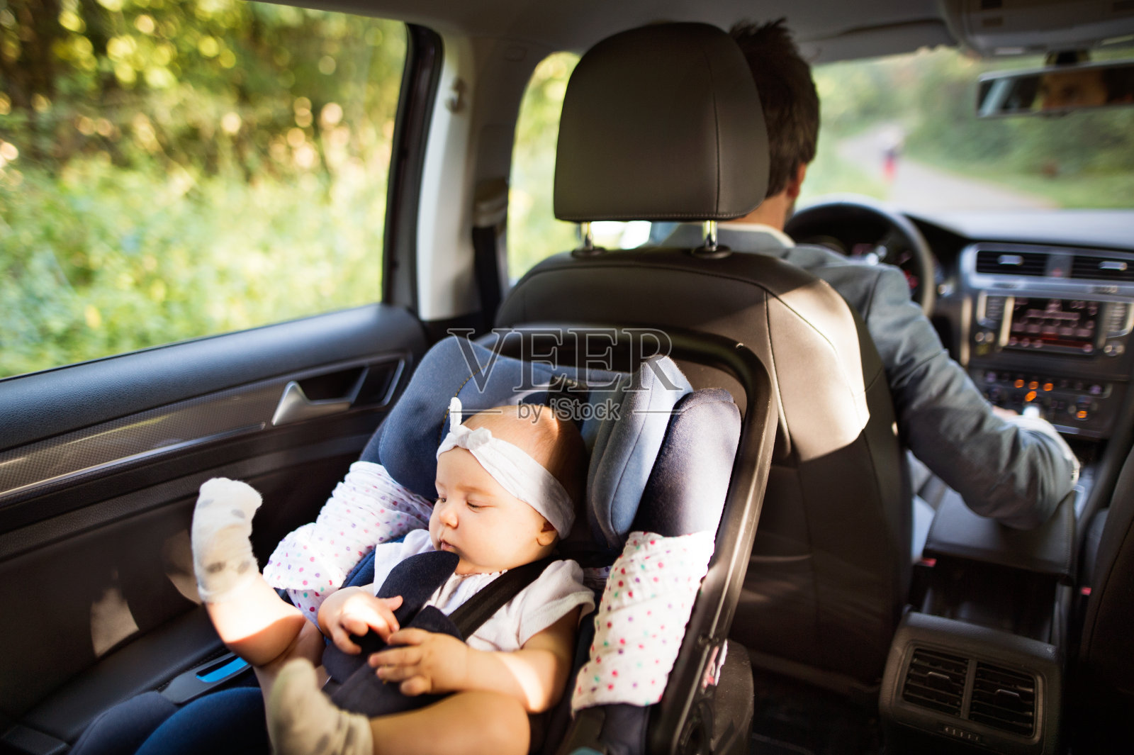 一个面目全非的男人带着一个女婴开车。照片摄影图片