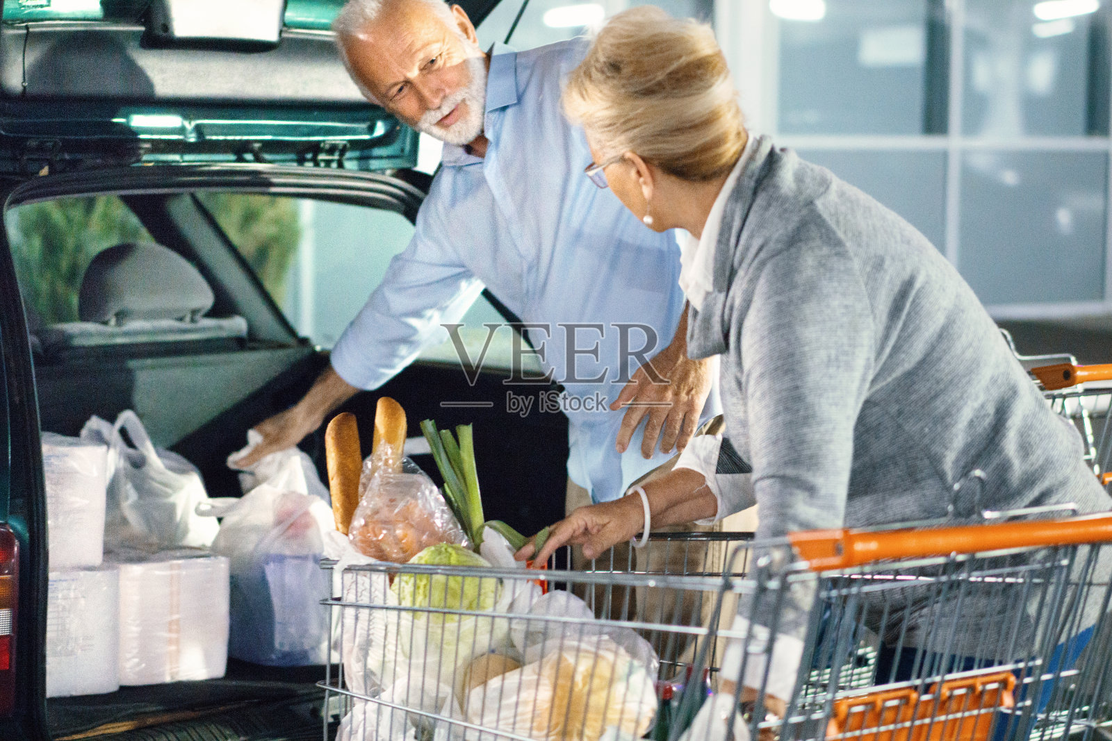 一对老年夫妇在购物后打包食品。照片摄影图片