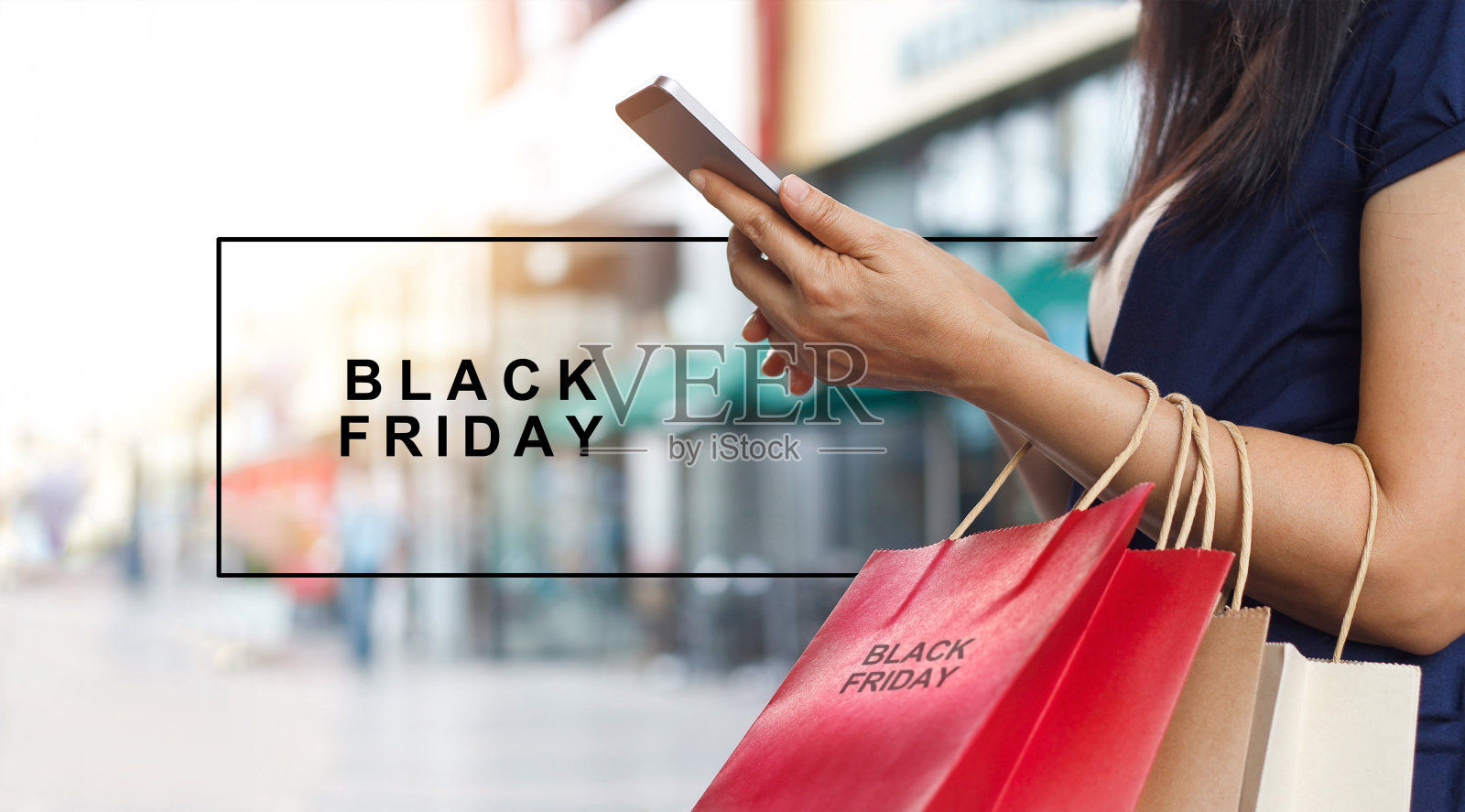 黑色星期五，站在商场背景上拿着购物袋拿着智能手机的女人照片摄影图片