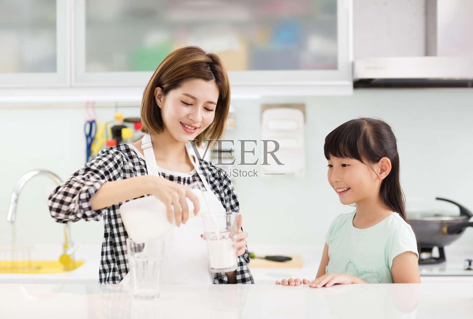 快乐的母亲和孩子在厨房喝牛奶照片摄影图片