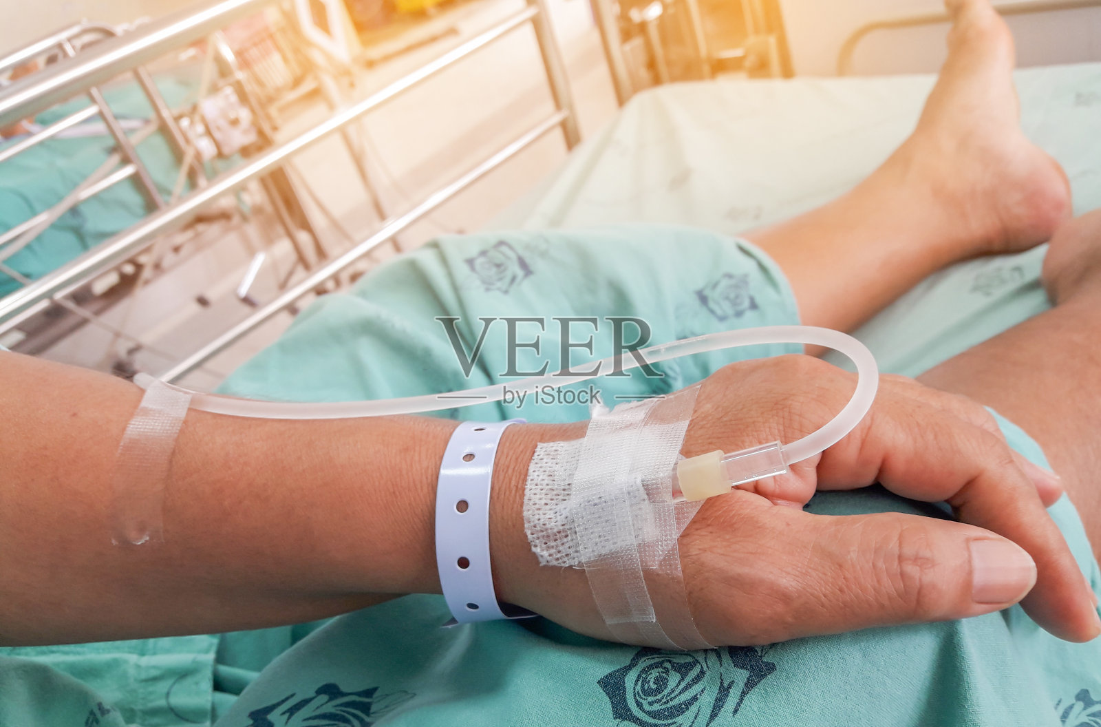 病人的双手正在医院的病床上点滴接受生理盐水。照片摄影图片