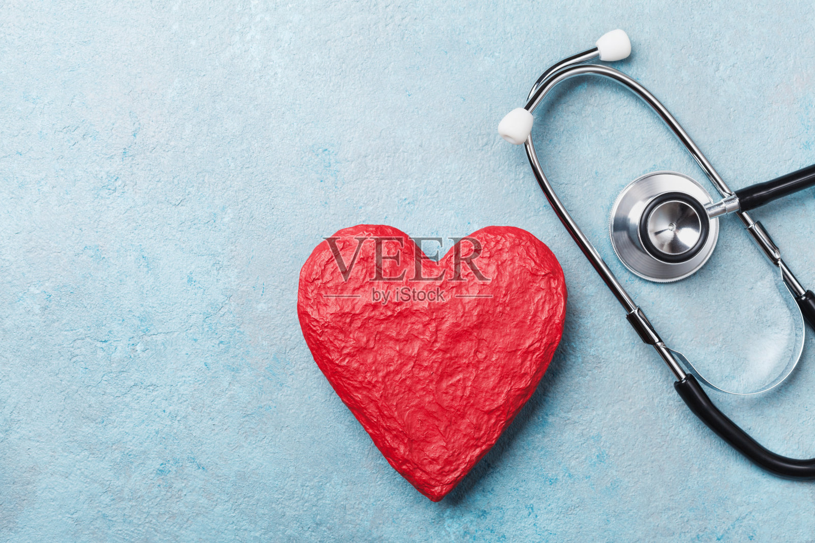 红色心脏形状和医疗听诊器在蓝色背景俯视图。医疗保健、医疗保险和心脏病学。照片摄影图片