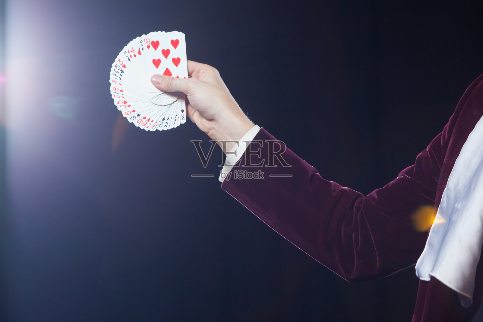 手与卡片特写。魔术师的腹部显示扇形的卡片在黑色的背景。魔术师，变戏法的人，有趣的人，黑魔法，幻觉照片摄影图片