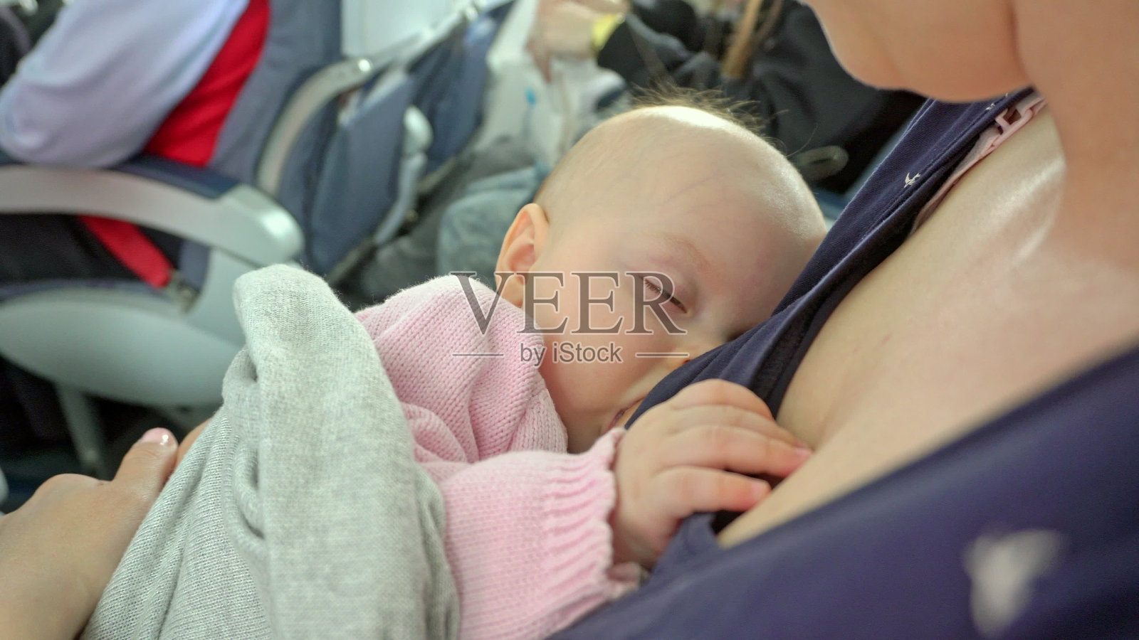 一名妇女在飞机上哺乳她的孩子照片摄影图片
