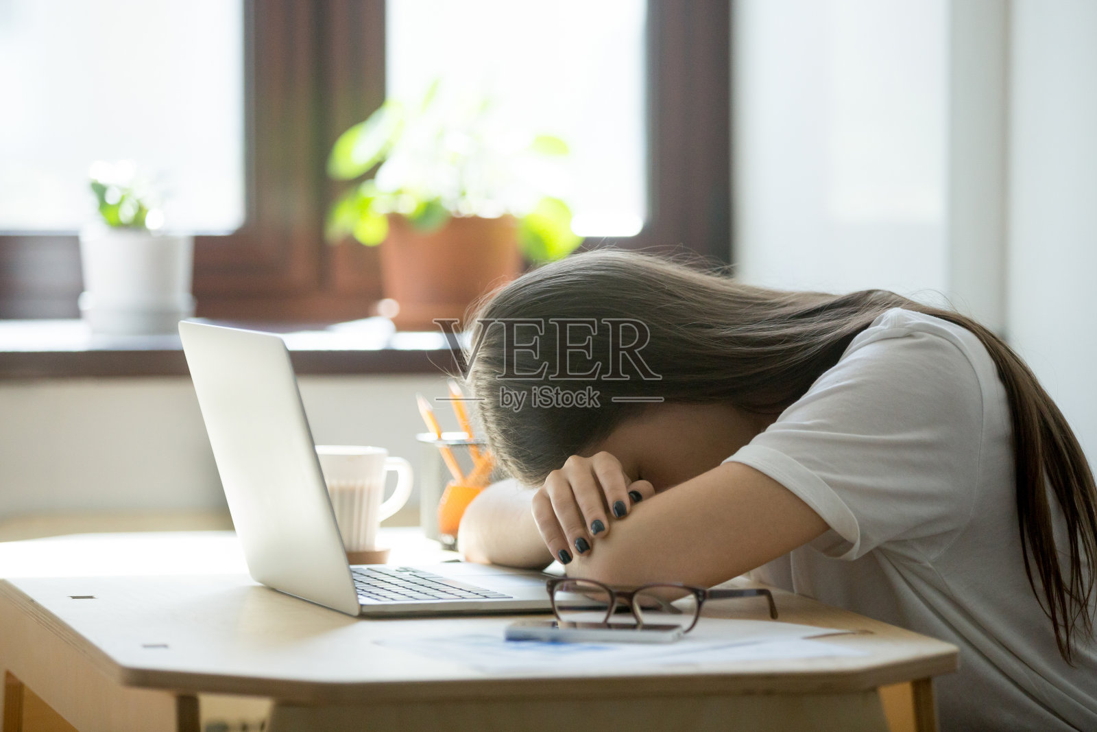 劳累过度，精疲力竭的女商人睡在家庭办公室的笔记本电脑上照片摄影图片