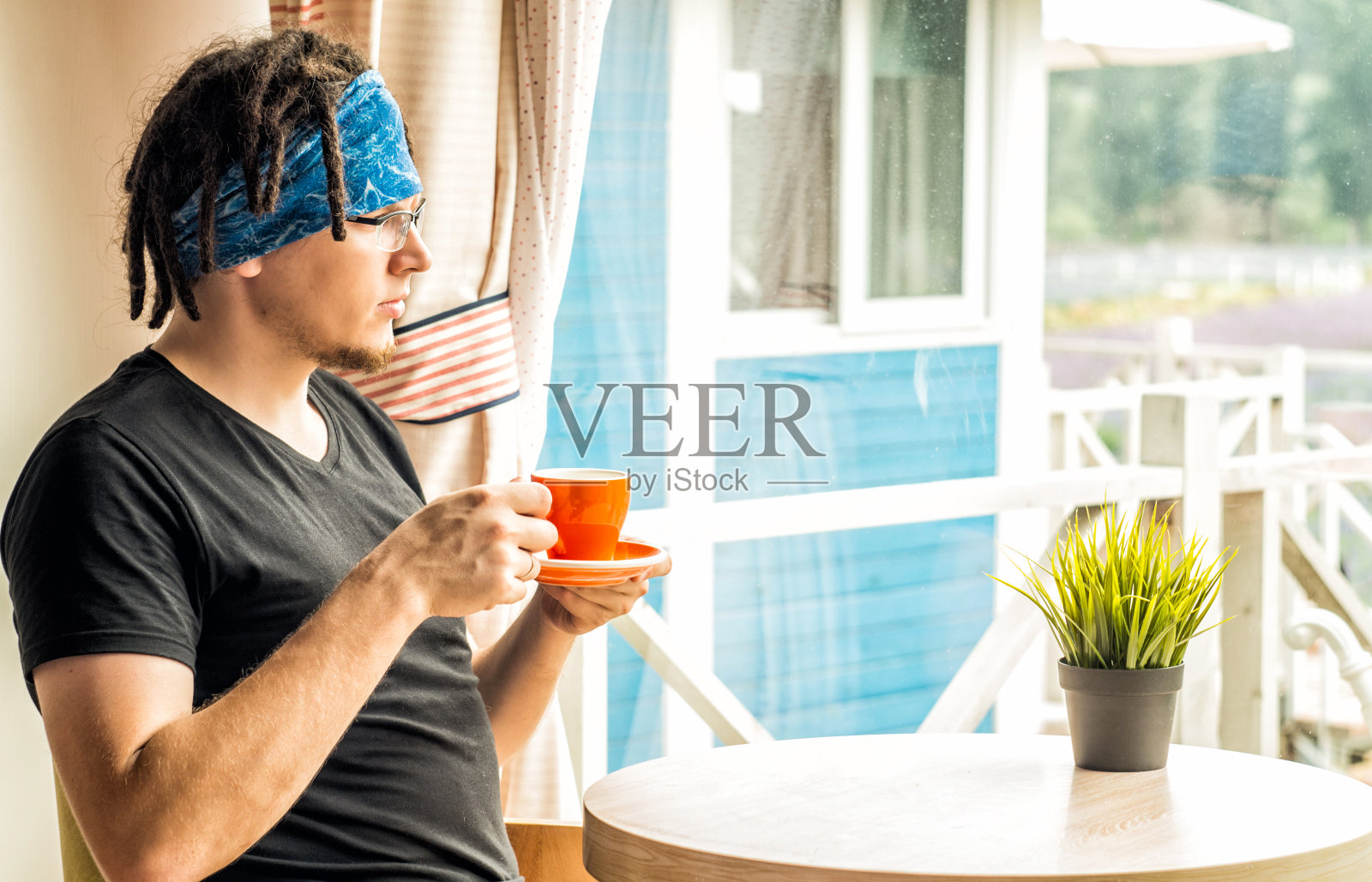 一个男人正在喝茶，看着窗户照片摄影图片