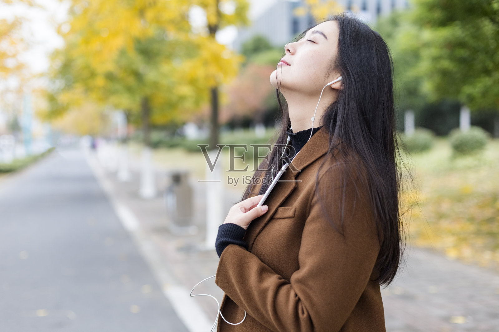 一个年轻女子在秋天的街上听音乐照片摄影图片