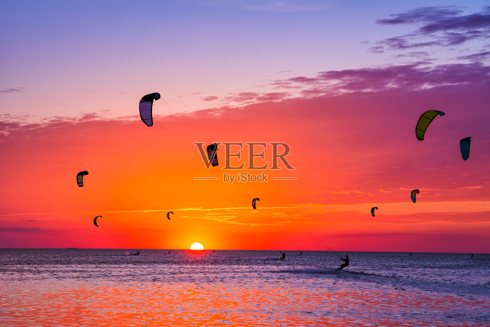 在美丽的夕阳下风筝冲浪。天空中有许多风筝的剪影。度假的本性。艺术照片。美丽的世界。照片摄影图片