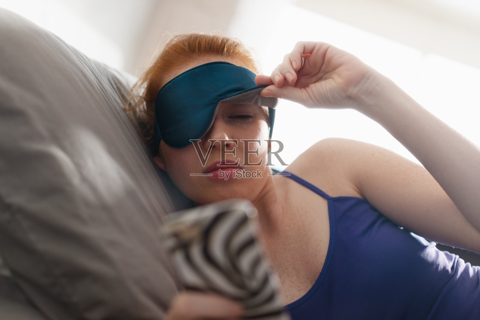 躺在床上的女人正在醒来的贪睡闹钟手机照片摄影图片