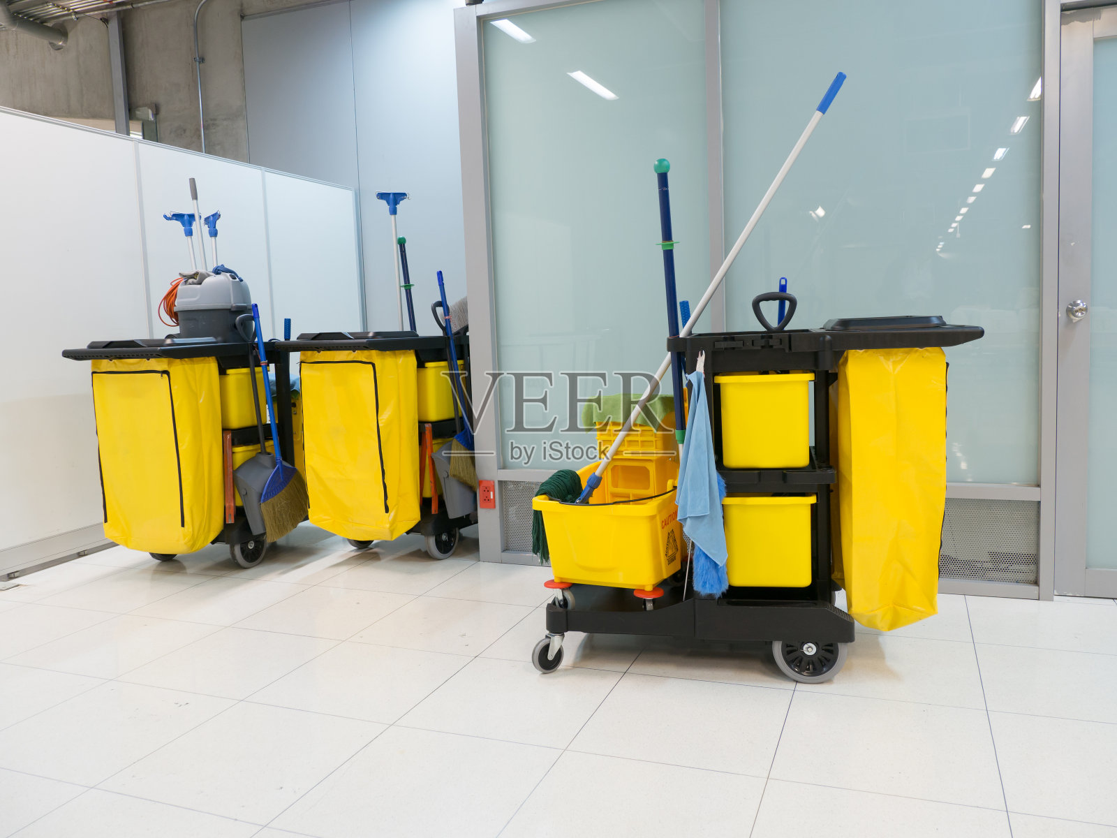 车站内的清洁车。清洁工具车和黄色拖把桶等待清洁。机场办公室的桶和清洁设备。照片摄影图片