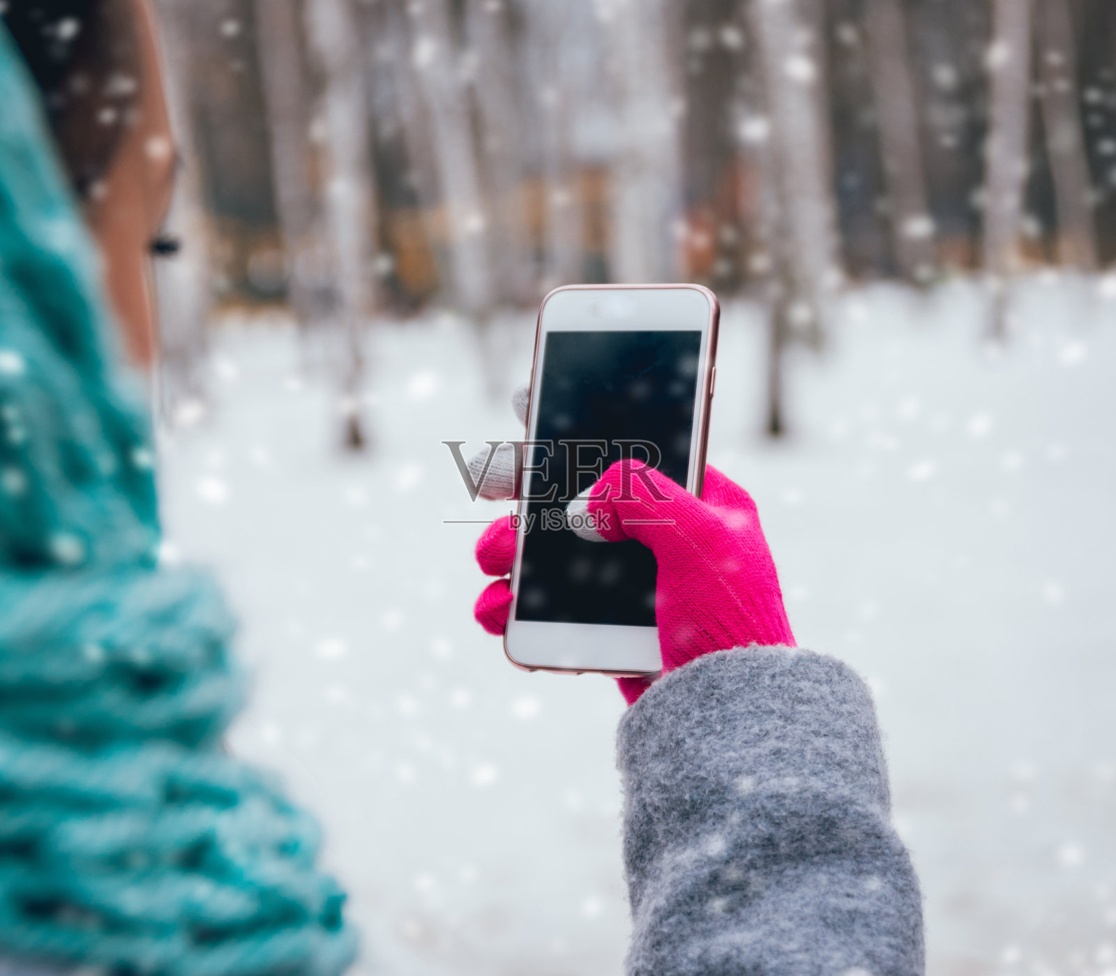 在冬天戴着触摸屏手套使用智能手机的女性照片摄影图片