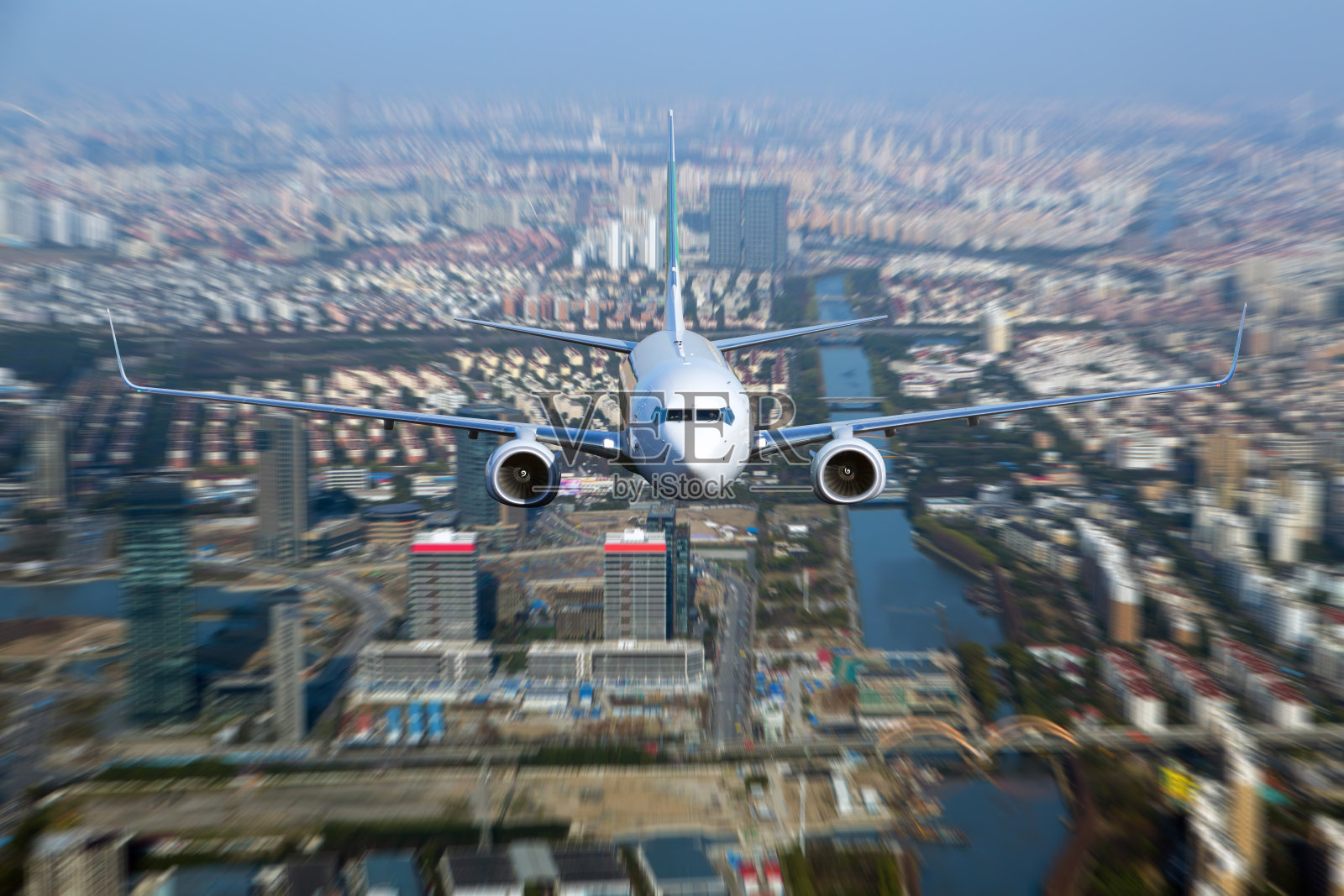 一架白色客机在城市上空飞行。照片摄影图片