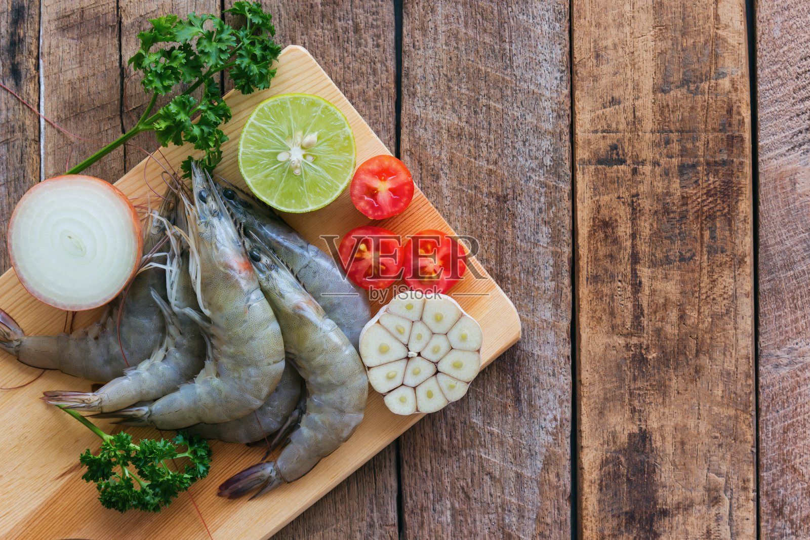 新鲜的白色虾在木材切板在俯视图平与复制空间。在木桌上为海鲜菜单准备生虾、蔬菜和香草。自制美味食物的概念。照片摄影图片