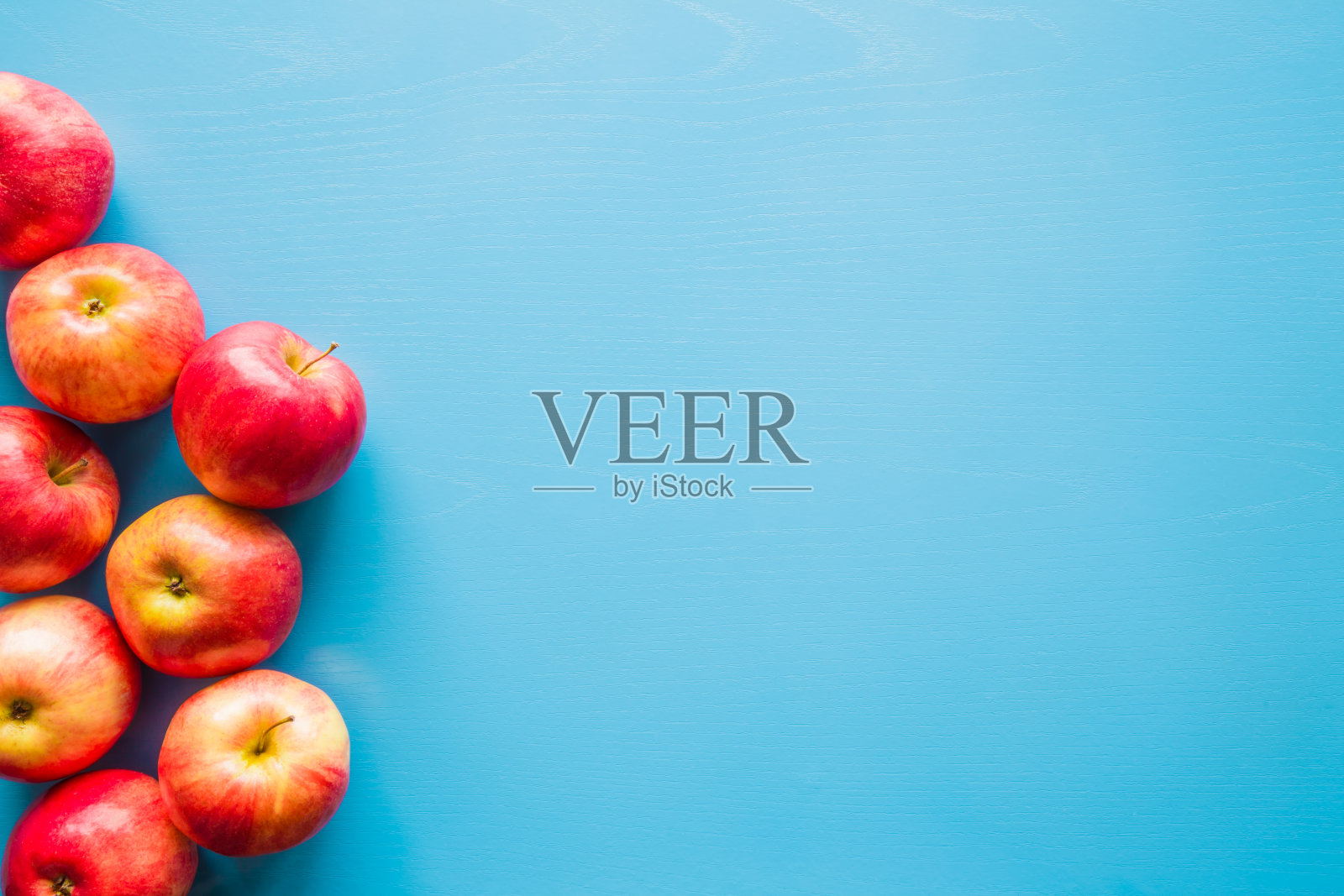 美丽，新鲜，彩色的苹果在蓝色的背景。健康甜食的概念。模拟水果提供作为广告或网络背景，或其他想法。文字或标识的空白位置。照片摄影图片