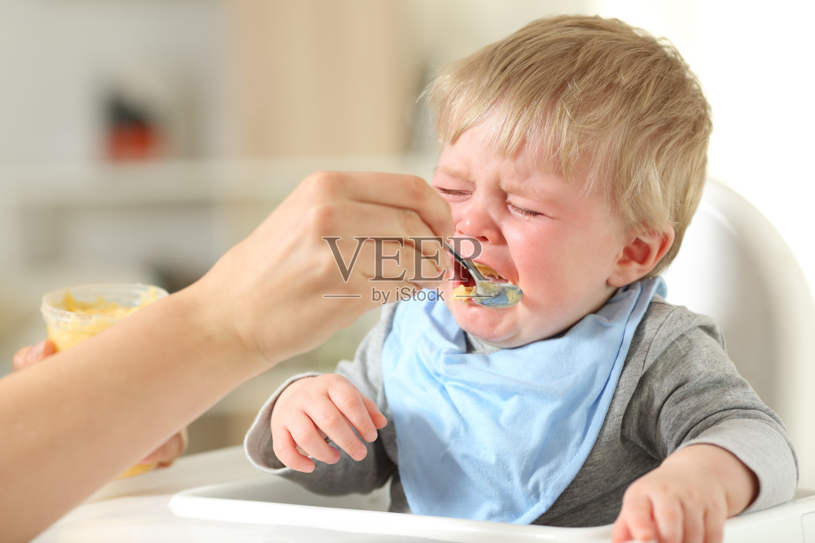 母亲给正在哭泣的儿子喂奶照片摄影图片