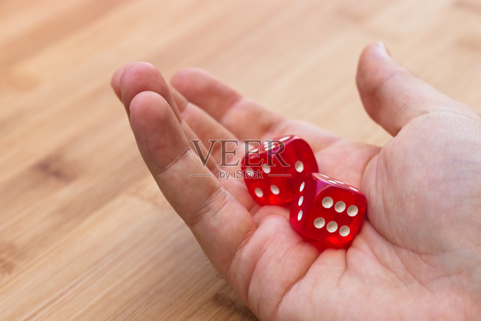 一只手拿着红色的骰子。这个图像可以用来代表赌博或冒险。照片摄影图片