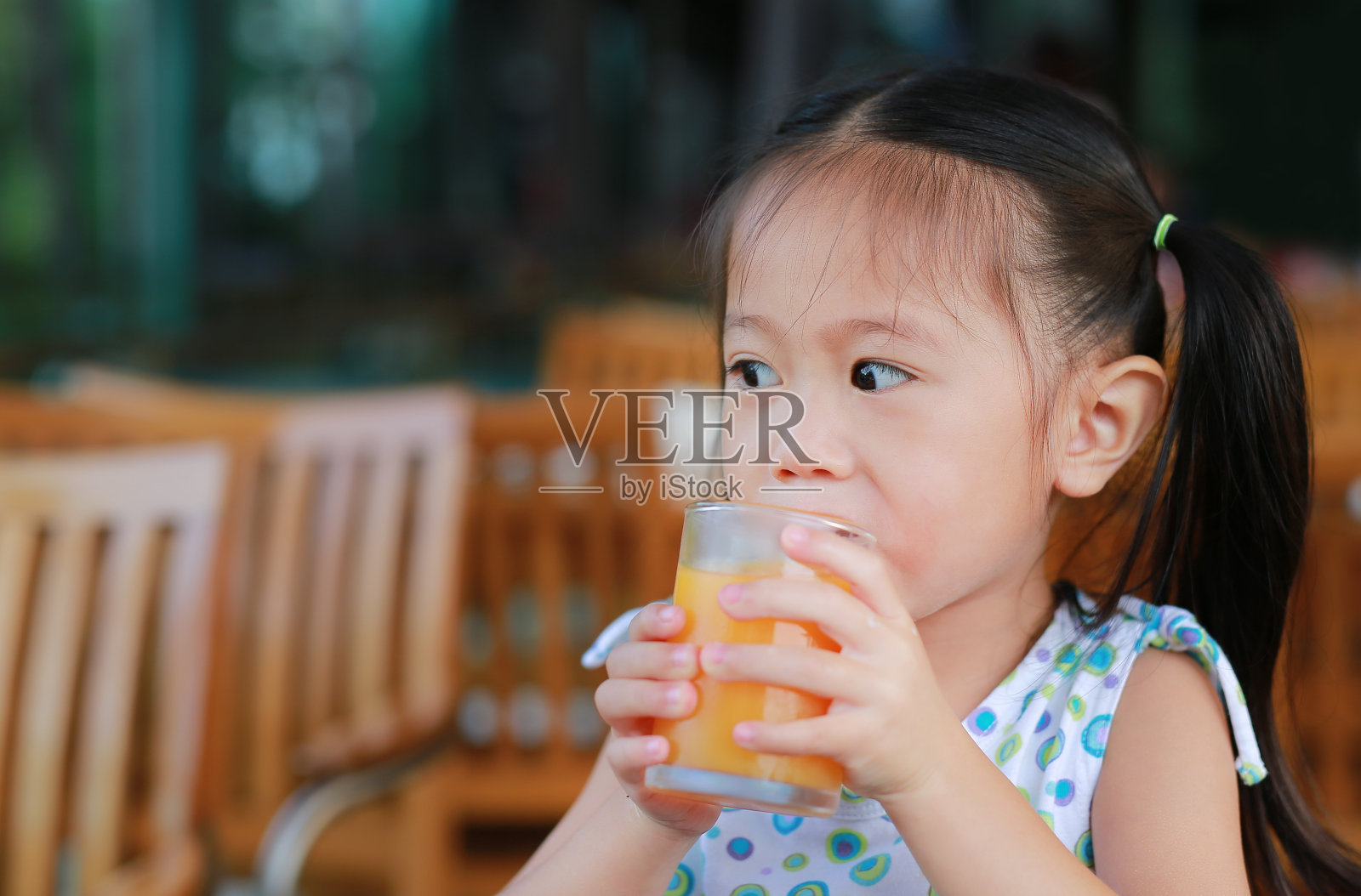 小女孩喝橙汁的特写镜头。照片摄影图片