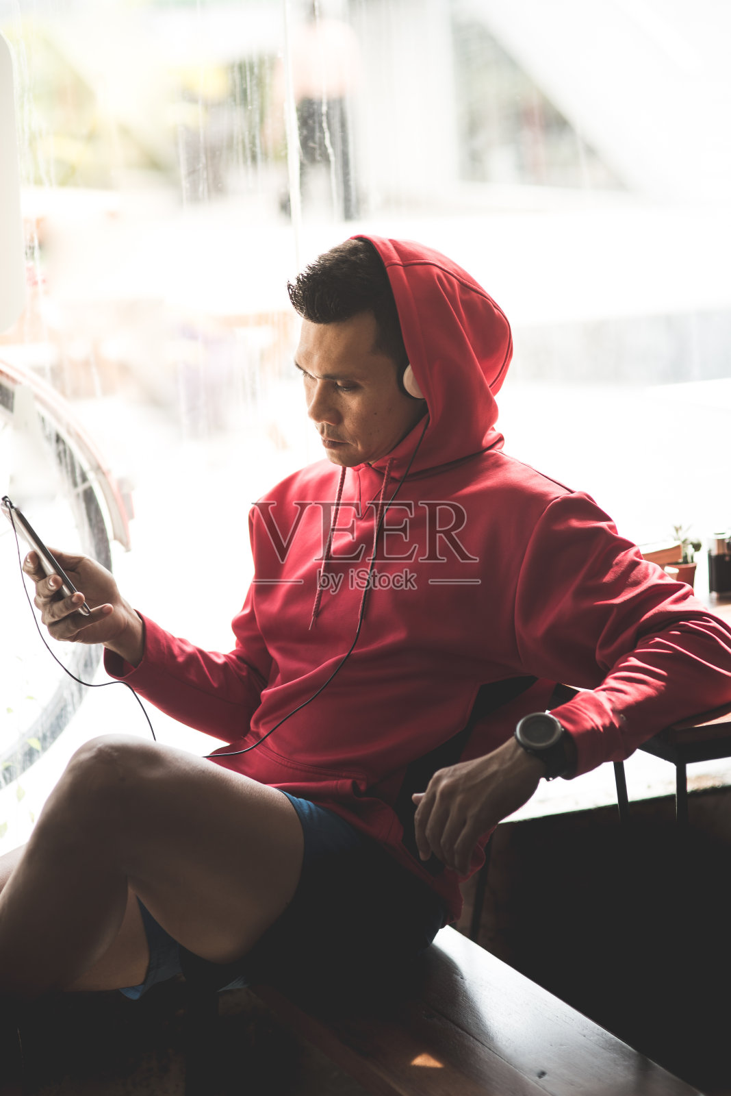 运动男子在红色头巾听音乐通过智能手机，现代生活理念。照片摄影图片