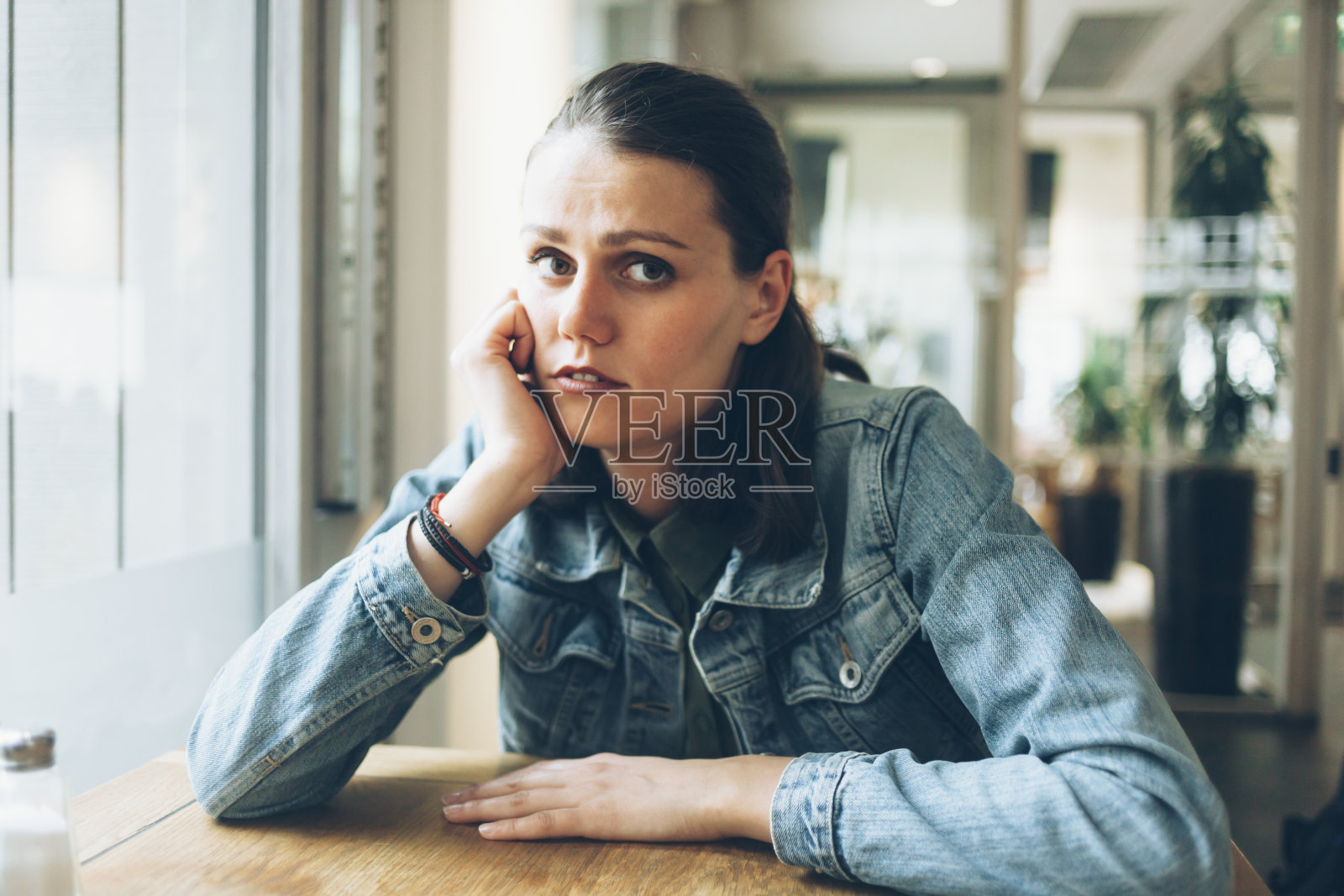 独自坐在咖啡馆里沉思的年轻女子照片摄影图片
